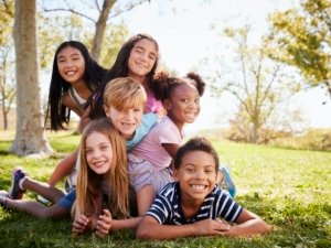 Multi-ethnic group of kids lying on each other in a park