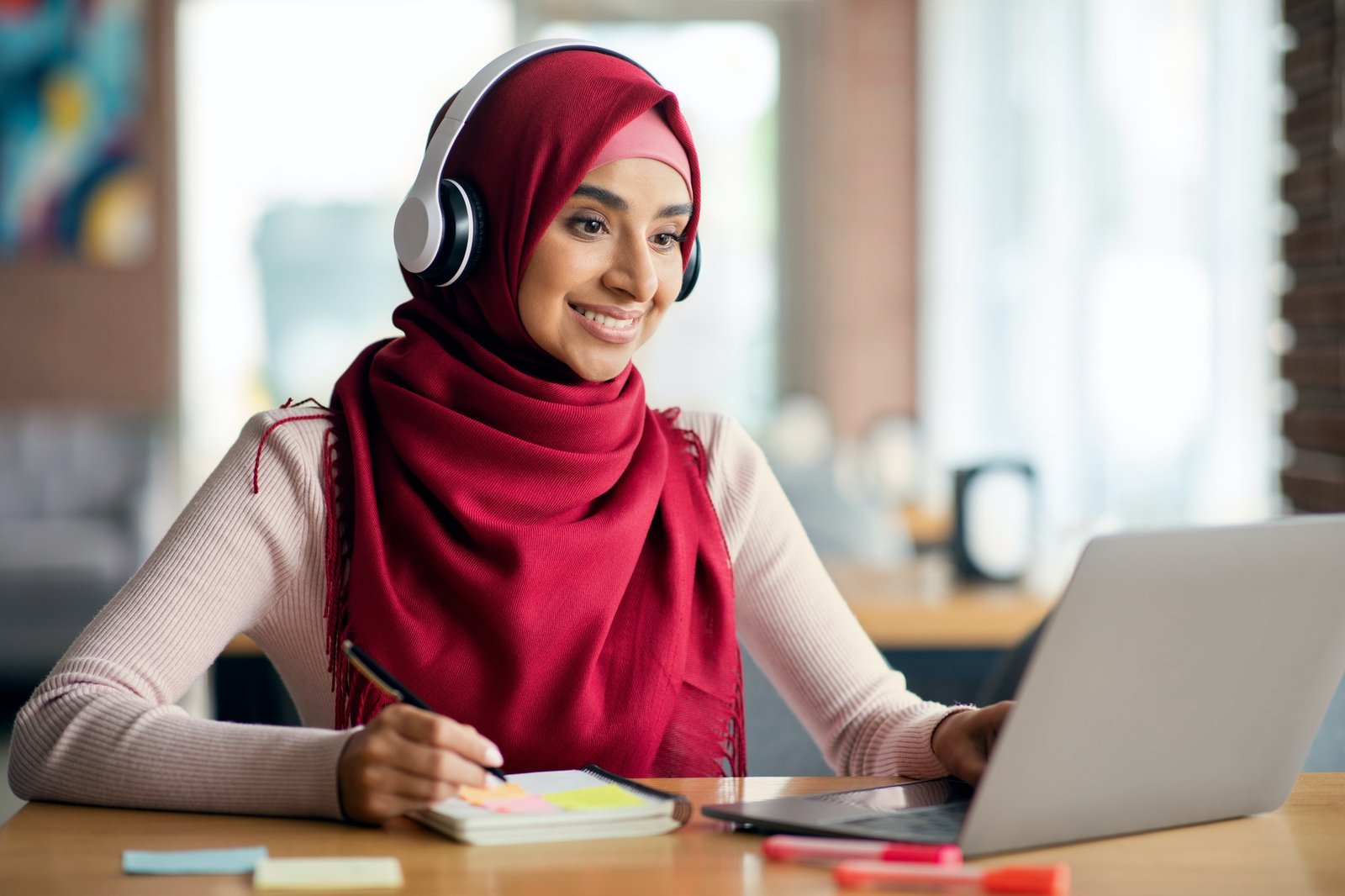 Joyful muslim woman attending online class, cafe interior, copy space