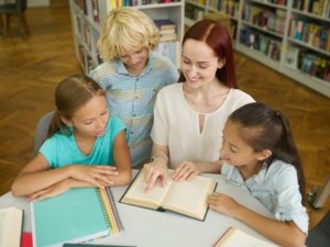 Woman teaching children to read at table