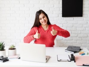 Young latin woman in black headphones teaching english online showing thumbs up