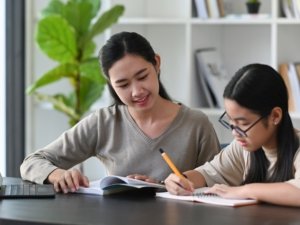 Young mother helping her daughter with homework at home.