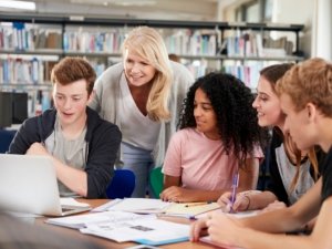 Female Teacher Working With College Students In Library