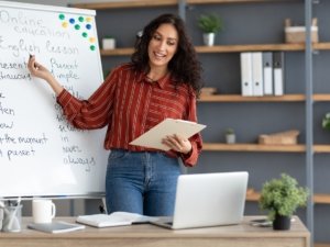 English teacher pointing on board, explaining theme to students online