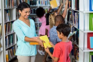 Teacher giving books to boy