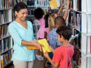 Teacher giving books to boy