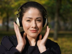 young woman listening to music with cordless headphones outside