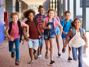 School kids running in elementary school hallway, front view
