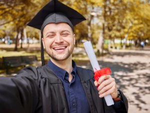 Man, graduation selfie and certificate for college student, smile and excited for future at campus
