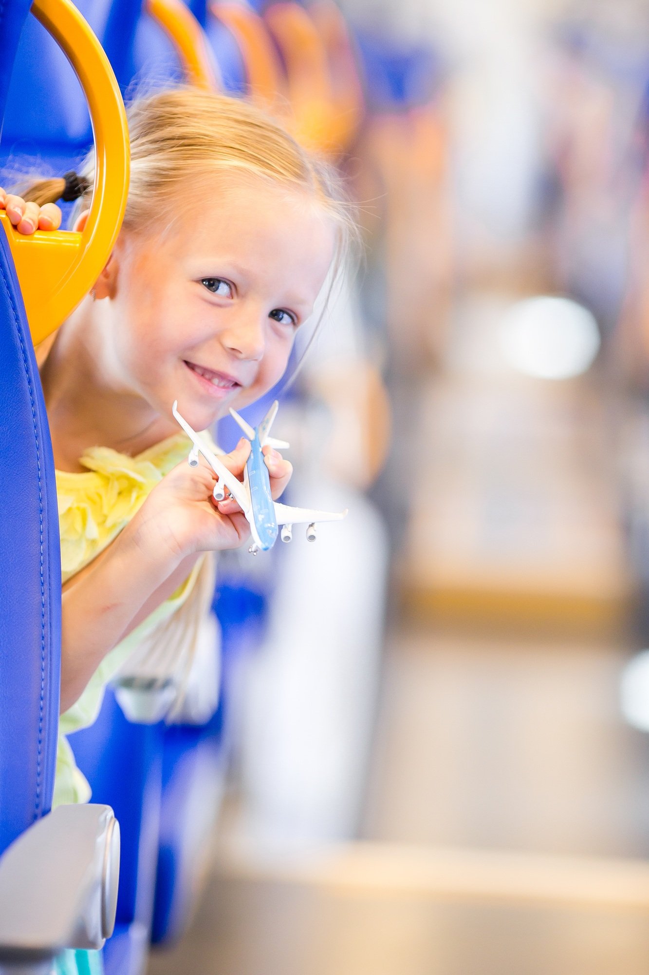 Adorable little girl traveling on train and having fun with airplane model in hands