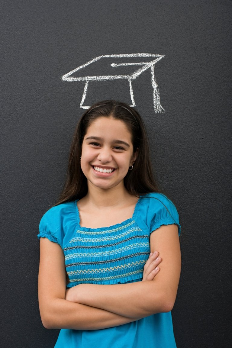 Young girl smiling with a chalk drawing of a graduation cap above her head