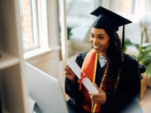 Happy black student showing her graduation diploma during a video call.