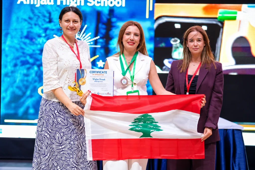Three women holding a certificate and the Lebanese flag at the Creative Teacher Award 2026 ceremony in Egypt.