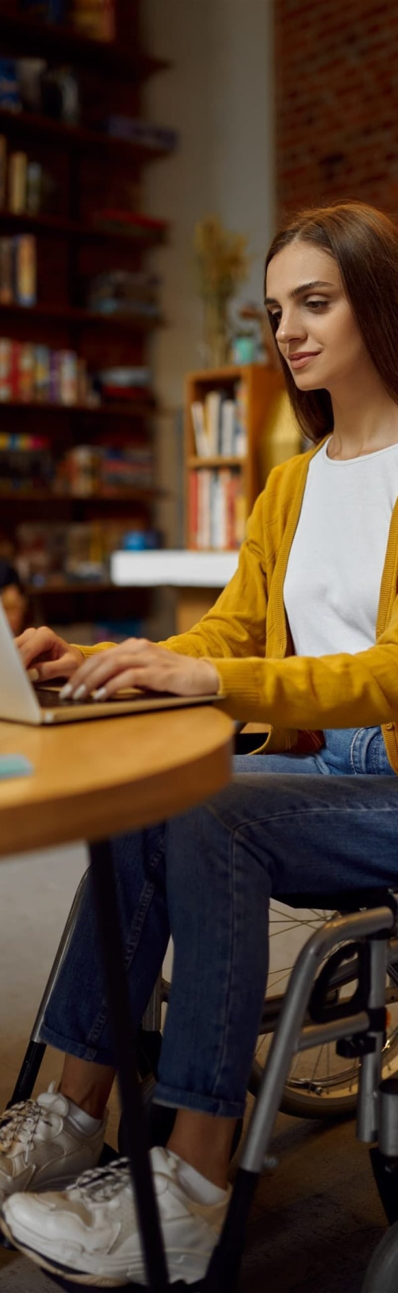 Disabled female student in wheelchair using laptop