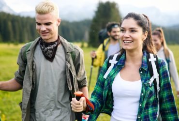 Gorup of friends climbing up hill, with backpacks and climbing stick