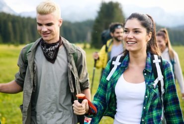 Gorup of friends climbing up hill, with backpacks and climbing stick